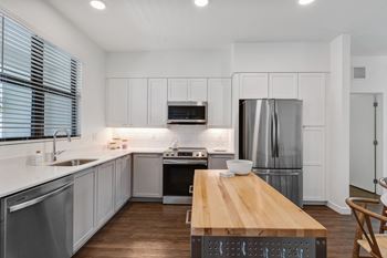 a kitchen with white cabinets and stainless steel appliances and a wooden table at Odyssey, Fort Myers, Florida
